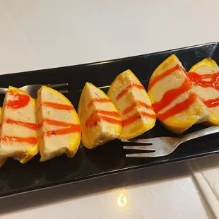 four slices of cheesecake on a black plate with a fork