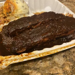 a plate of ribs and mashed potatoes