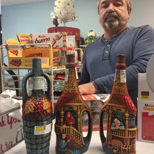 a man standing in front of three bottles of wine