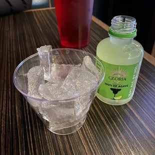 a glass of ice and a bottle of soda on a table