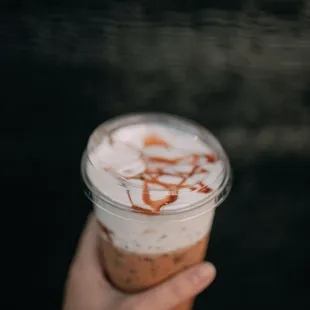 a hand holding a cup of iced coffee