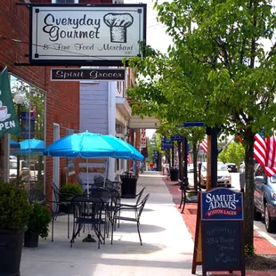a sidewalk with tables and umbrellas