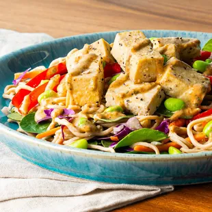 a bowl of noodles with tofu and vegetables