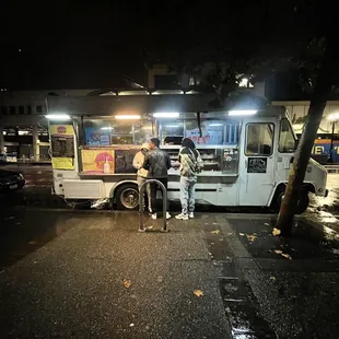 a man and a woman standing in front of a food truck