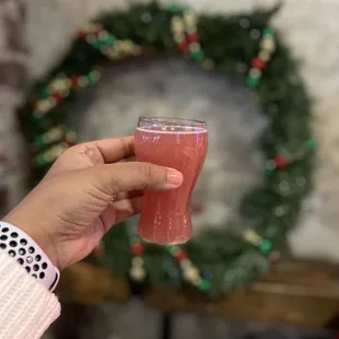 a hand holding a glass of red liquid