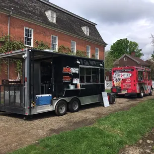 two food trucks parked in front of a brick building