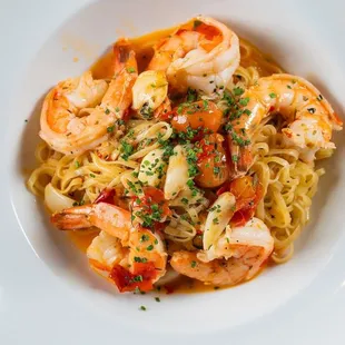 a plate of pasta with shrimp and tomatoes