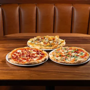 three pizzas on plates on a table