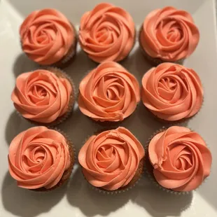 a plate of cupcakes with pink frosting