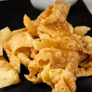 a pile of fried tortillas on a black plate