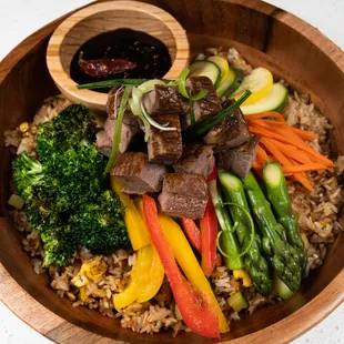 a wooden bowl filled with rice and vegetables