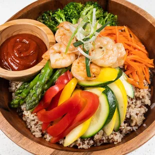 a wooden bowl filled with vegetables and shrimp