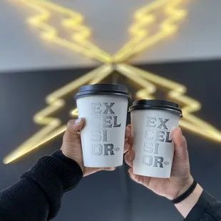 two people holding coffee cups