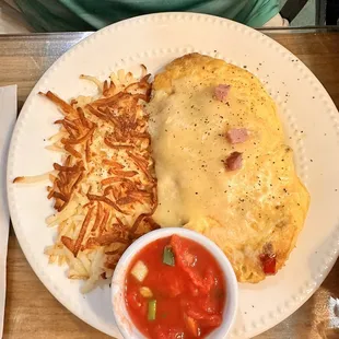 an omelet, hash browns, and tomato sauce