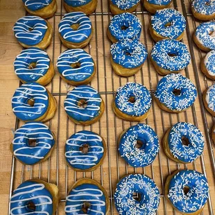 blue and white frosted donuts on a cooling rack