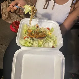 a woman eating a salad with chopsticks