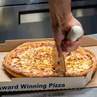 a person cutting a pizza in a box