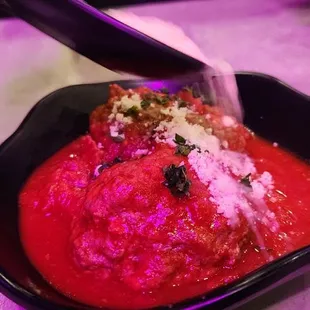 Husband pouring the parmesan cheese over the meat balls