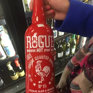 a person holding a bottle of hot sauce