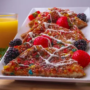 a plate of fruit pizza and a glass of orange juice