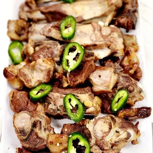 a plate of grilled meat with jalapenos