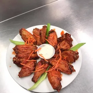 a plate of chicken wings with ranched carrots and celery