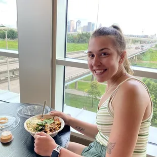 a woman sitting at a table with a bowl of food