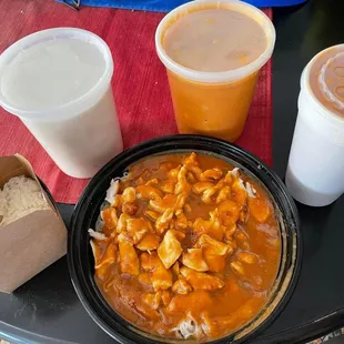 a bowl of chicken curry, rice, and drinks