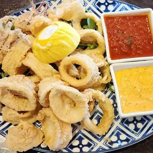 a blue and white plate with fried squids and dipping sauce