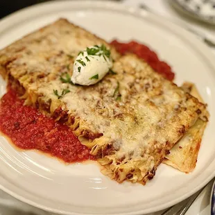 a plate of lasagna with a dollop of sour cream