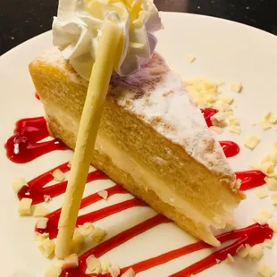 a slice of cake with whipped cream and raspberry sauce
