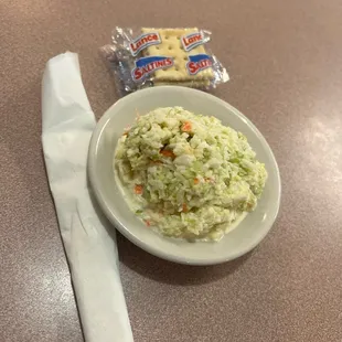 a bowl of coleslaw and a bag of chips