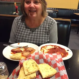 a woman sitting at a table with a plate of pizza