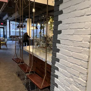 a wooden swing hanging from a brick wall