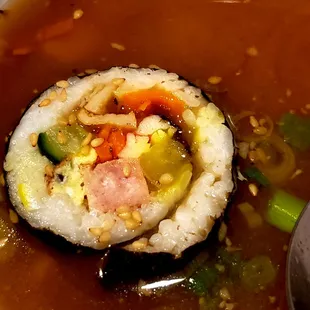 dunking a piece of kimbap (korean sushi w meat, veggie, rice) into miso soup
