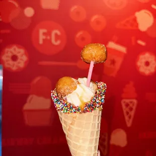 a hand holding a cone with a cone of ice cream and sprinkles