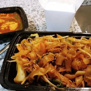 a bowl of noodles and a container of soup