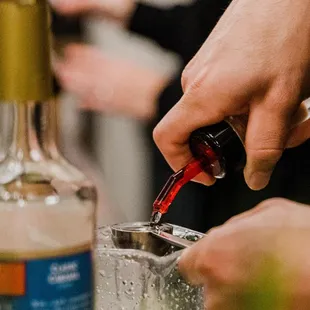 a person pouring a drink into a glass