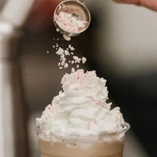 a person scooping whipped cream into a cup