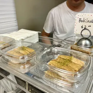 a man behind a counter with trays of food