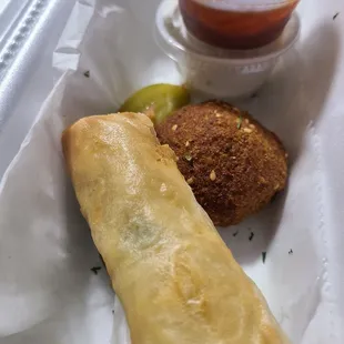 a tray of food including a falafe and a cup of sauce