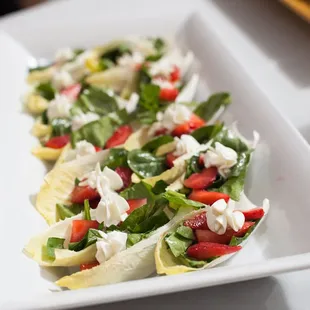 Summer salad cups. Baby spinach, strawberries, pomegranate vinaigrette and chevre flowers, inside edable endive cups