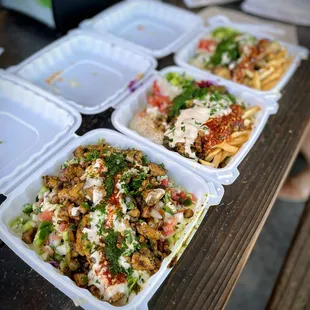 four takeout containers of food on a picnic table