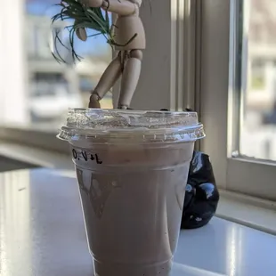 a cup of coffee with a doll on top