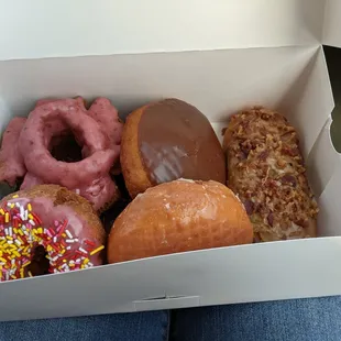 box of donuts: maple bacon, raspberry old fashion, sprinkle, raspberry filled, chocolate creme-filled