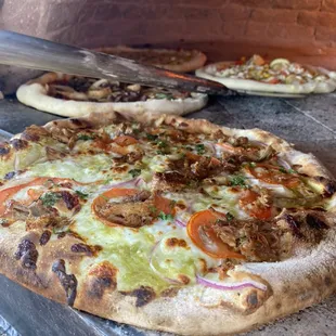 Tomatillo pizza! Parmesan, fresh mozzarella, tomatillo salsa, sliced roma tomatoes, red onions, carnitas (shredded pork) , cilantro