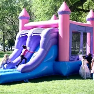 Pink Combo Castle featuring 2 slides, basketball hoop, pop ups and netted ceiling