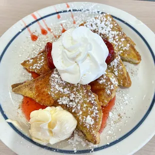 a plate of pancakes with whipped cream and strawberries