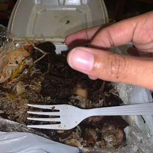 a hand holding a fork over a plate of food