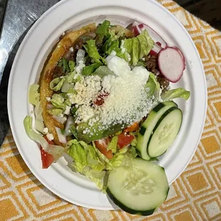 a white plate with a salad and cucumbers
